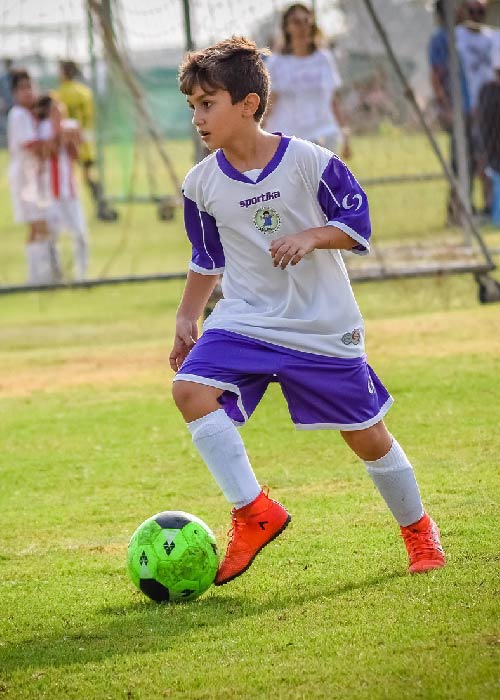 Young football player running with a ball during a match – illustration of athlete screening for the Horizon Europe project.